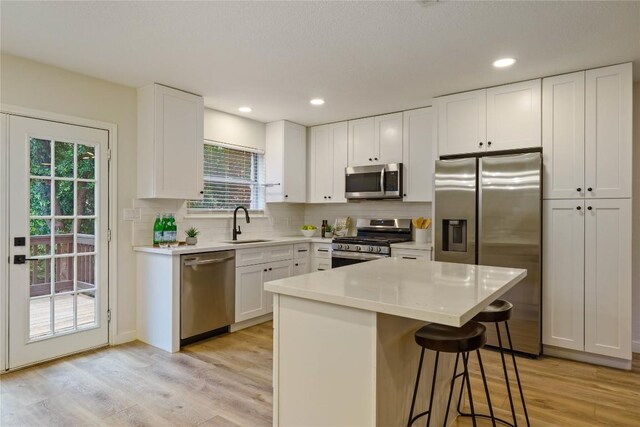 4507 Elana Ct, Austin, TX 78741 - kitchen with appliances with stainless steel finishes, light wood-style flooring, tasteful backsplash, a sink, and recessed lighting