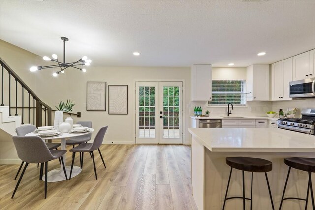 4507 Elana Ct, Austin, TX 78741 - kitchen featuring stainless steel appliances, light wood-style flooring, a breakfast bar area, light countertops, and a chandelier