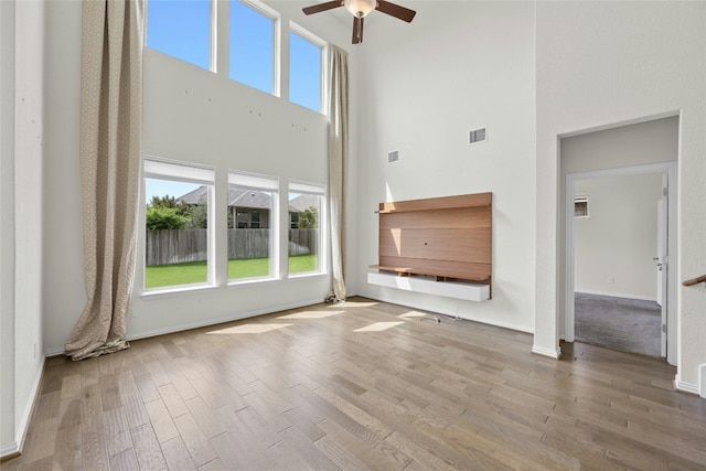 6724 Leonardo Dr, Round Rock, TX 78665 - unfurnished living room with a towering ceiling, a ceiling fan, wood finished floors, and baseboards