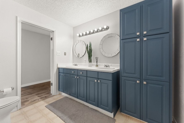 744 Jim Bowie Dr, Spicewood, TX 78669 - full bathroom with double vanity, toilet, and a textured ceiling