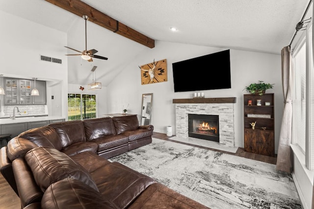 744 Jim Bowie Dr, Spicewood, TX 78669 - living area with ceiling fan, wood finished floors, a stone fireplace, a textured ceiling, and baseboards