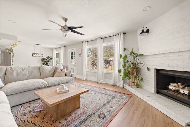 11200 Bending Bough Trl, Austin, TX 78758 - living room featuring ceiling fan, wood finished floors, a brick fireplace, a textured ceiling, and baseboards
