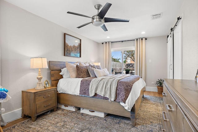 11200 Bending Bough Trl, Austin, TX 78758 - bedroom with a barn door, access to exterior, baseboards, wood finished floors, and recessed lighting