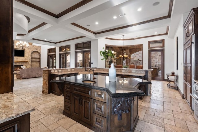 604 Logans Ln, Austin, TX 78746 - kitchen with stone tile floors, a chandelier, a large island, a large fireplace, and crown molding