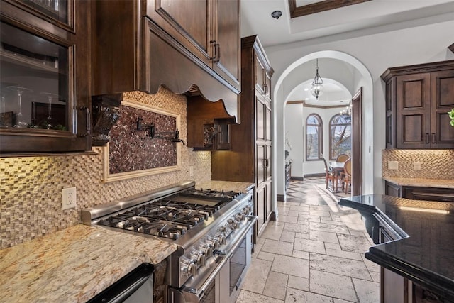 604 Logans Ln, Austin, TX 78746 - kitchen with double oven range, arched walkways, stone tile flooring, dark brown cabinetry, and decorative backsplash