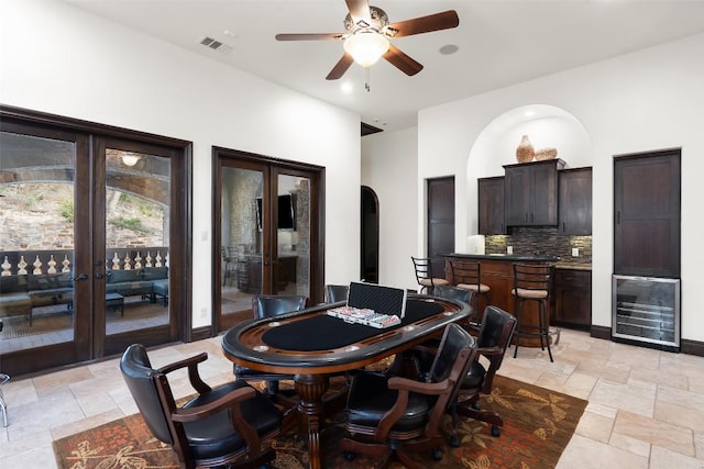 604 Logans Ln, Austin, TX 78746 - dining area featuring french doors, stone tile floors, beverage cooler, a ceiling fan, and arched walkways