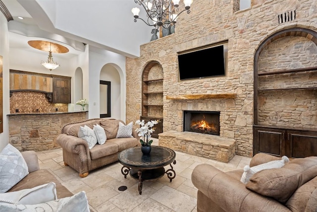 604 Logans Ln, Austin, TX 78746 - living room with built in shelves, a towering ceiling, stone tile flooring, a chandelier, and a fireplace
