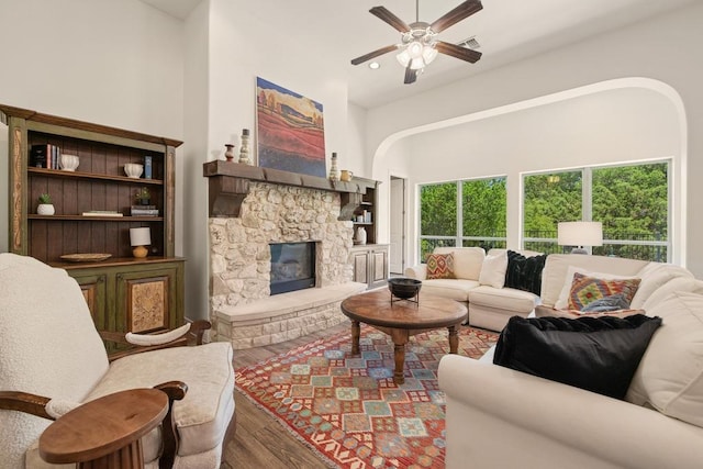 310 Lauren Trl, Cedar Park, TX 78613 - living room with wood finished floors, ceiling fan, a fireplace, a towering ceiling, and arched walkways