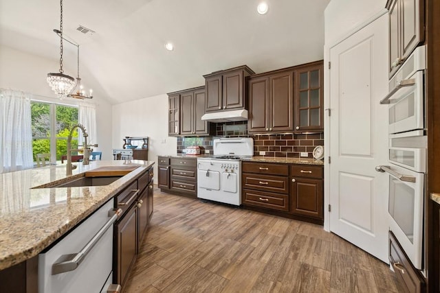310 Lauren Trl, Cedar Park, TX 78613 - kitchen featuring white appliances, a sink, vaulted ceiling, backsplash, and dark brown cabinetry