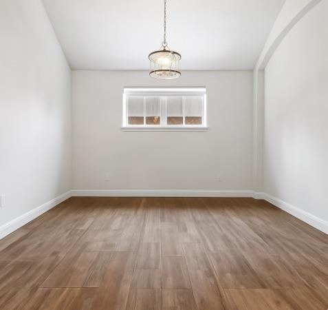 310 Lauren Trl, Cedar Park, TX 78613 - spare room with a chandelier, wood finished floors, and baseboards