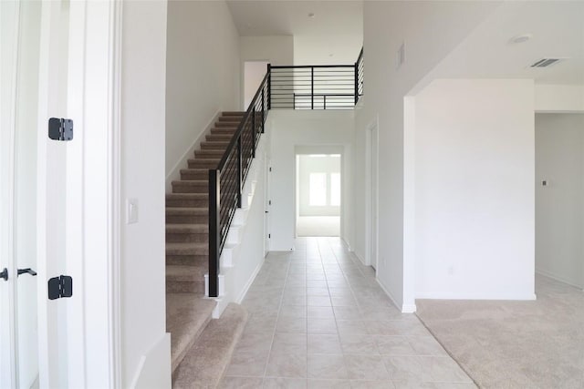 5337 Olimpico Way, Leander, TX 78641 - foyer entrance featuring stairs, light tile patterned flooring, a high ceiling, baseboards, and light carpet
