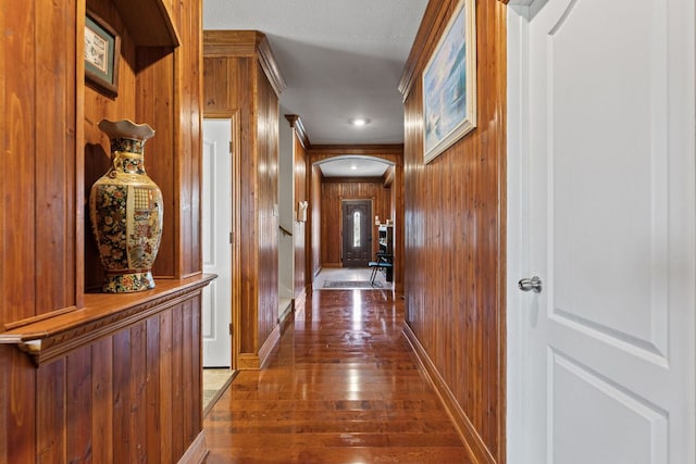 113 Blossom Valley Strm, Buda, TX 78610 - hallway featuring wood walls, dark wood-style flooring, arched walkways, and baseboards