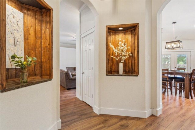 119 Tallwood Cir, Salado, TX 76571 - hallway with arched walkways, a chandelier, wood finished floors, and baseboards