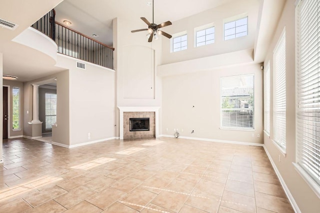 7701 Crackling Creek Dr, Austin, TX 78736 - unfurnished living room featuring a ceiling fan, a high ceiling, baseboards, a tile fireplace, and decorative columns