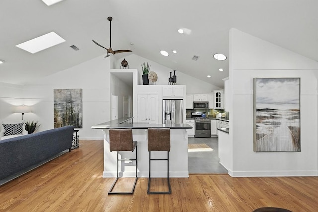 905 Juanita St, Austin, TX 78704 - kitchen with stainless steel appliances, dark countertops, high vaulted ceiling, white cabinets, and open floor plan