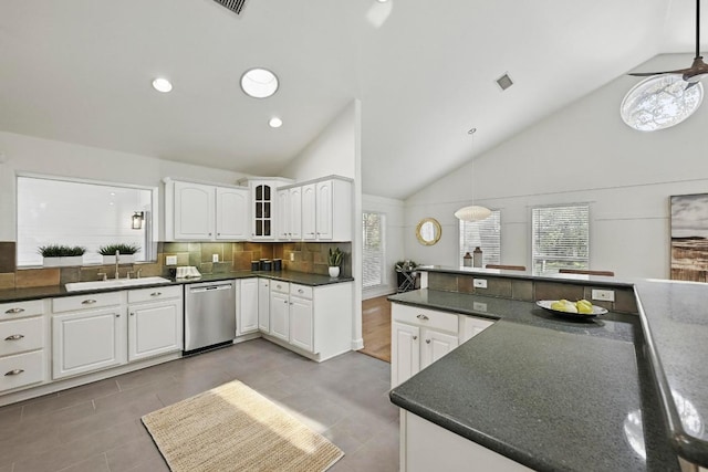 905 Juanita St, Austin, TX 78704 - kitchen with stainless steel dishwasher, dark countertops, a sink, white cabinetry, and decorative backsplash