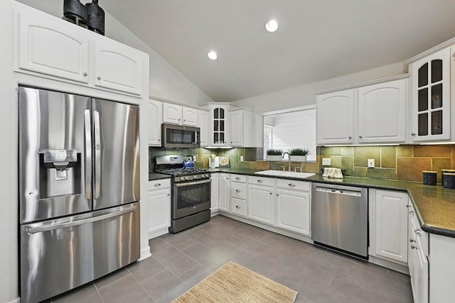 905 Juanita St, Austin, TX 78704 - kitchen with appliances with stainless steel finishes, a sink, dark countertops, glass insert cabinets, and lofted ceiling