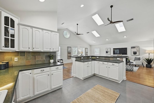 905 Juanita St, Austin, TX 78704 - kitchen with a skylight, open floor plan, tile patterned flooring, high vaulted ceiling, and glass insert cabinets