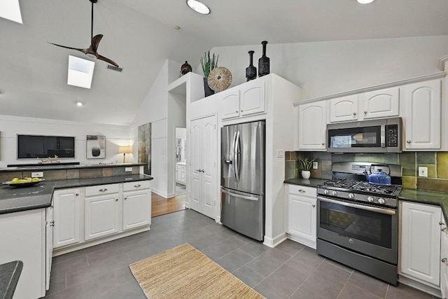 905 Juanita St, Austin, TX 78704 - kitchen featuring appliances with stainless steel finishes, dark countertops, decorative backsplash, white cabinetry, and high vaulted ceiling