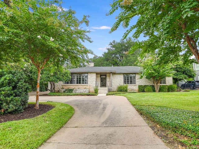 3304 Windsor Rd, Austin, TX 78703 - view of front facade with stone siding, a front yard, concrete driveway, and a chimney