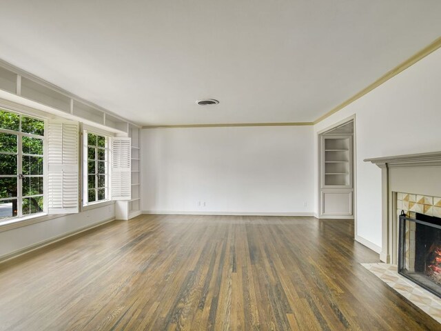 3304 Windsor Rd, Austin, TX 78703 - unfurnished living room featuring wood finished floors, a tiled fireplace, built in features, and ornamental molding