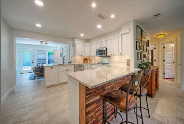 5606 Longhorn Lndg, Austin, TX 78734 - kitchen featuring a peninsula, stainless steel appliances, a sink, a kitchen breakfast bar, and recessed lighting