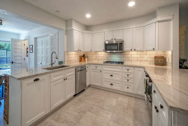 5606 Longhorn Lndg, Austin, TX 78734 - kitchen with appliances with stainless steel finishes, a peninsula, a sink, white cabinetry, and decorative backsplash