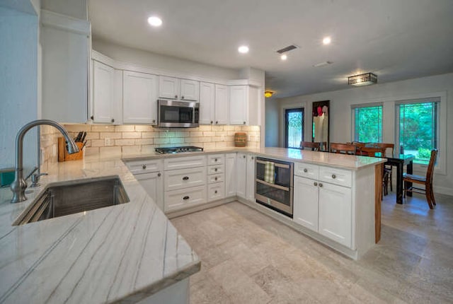 5606 Longhorn Lndg, Austin, TX 78734 - kitchen with a sink, a peninsula, appliances with stainless steel finishes, tasteful backsplash, and white cabinets