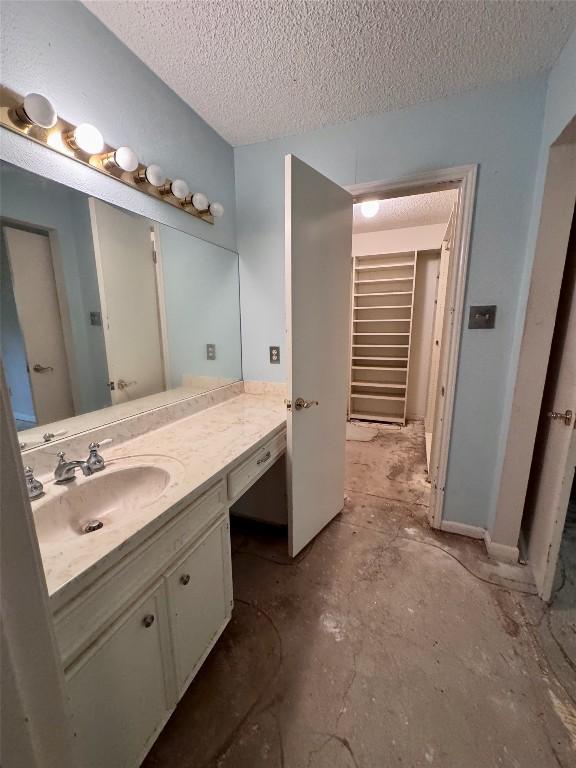 3409 Rosefinch Trl, Austin, TX 78746 - bathroom with vanity, a textured ceiling, and concrete floors
