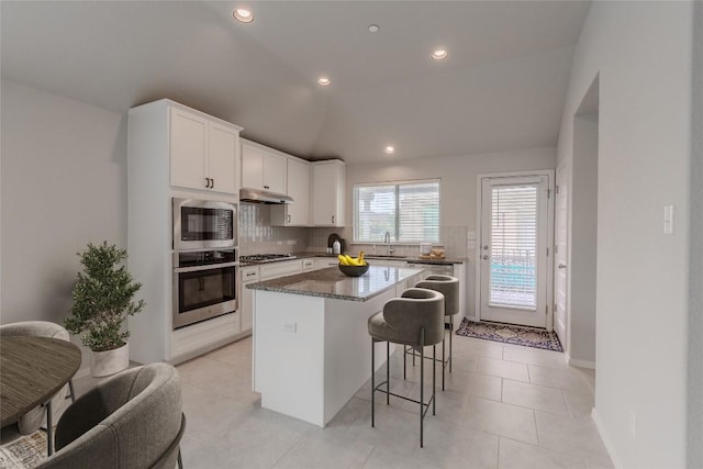 2800 Joe Dimaggio Blvd Unit 95, Round Rock, TX 78665 - kitchen featuring appliances with stainless steel finishes, under cabinet range hood, a kitchen bar, a kitchen island, and decorative backsplash