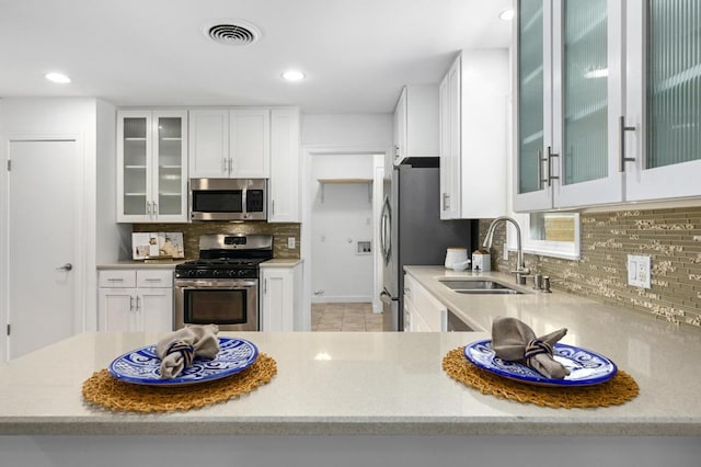 1802 Corona Dr, Austin, TX 78723 - kitchen with stainless steel appliances, backsplash, white cabinets, light tile patterned floors, and recessed lighting