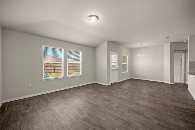 144 Sulphur River Loop, Hutto, TX 78634 - unfurnished living room featuring a chandelier, plenty of natural light, dark wood-style flooring, baseboards, and a textured ceiling