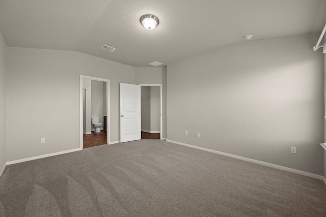 144 Sulphur River Loop, Hutto, TX 78634 - unfurnished bedroom with dark colored carpet, lofted ceiling, baseboards, and ensuite bathroom