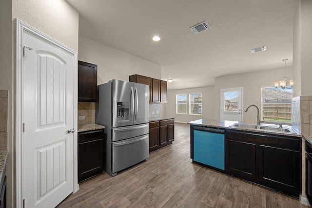 144 Sulphur River Loop, Hutto, TX 78634 - kitchen with stainless steel fridge, dishwasher, light wood-style flooring, a sink, and tasteful backsplash