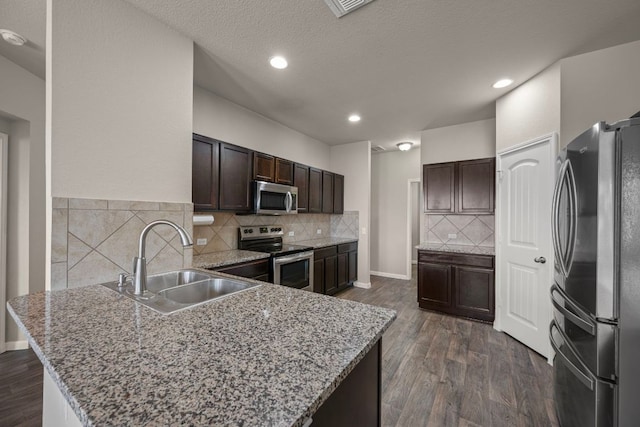 144 Sulphur River Loop, Hutto, TX 78634 - kitchen featuring stainless steel appliances, a sink, dark brown cabinetry, dark wood finished floors, and a peninsula
