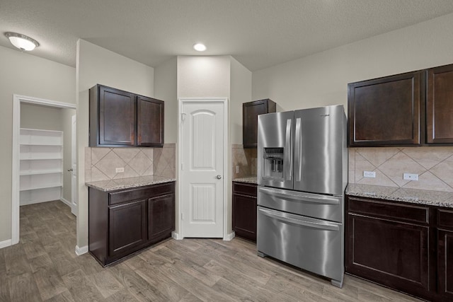 144 Sulphur River Loop, Hutto, TX 78634 - kitchen featuring stainless steel fridge, light wood-style floors, dark brown cabinetry, and a textured ceiling