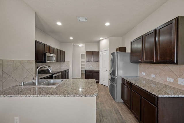 144 Sulphur River Loop, Hutto, TX 78634 - kitchen featuring stainless steel appliances, backsplash, dark brown cabinets, a sink, and recessed lighting