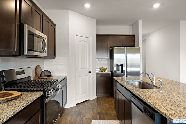 809 Cade Cv, Georgetown, TX 78626 - kitchen featuring appliances with stainless steel finishes, a sink, dark wood-style floors, dark brown cabinetry, and light stone countertops