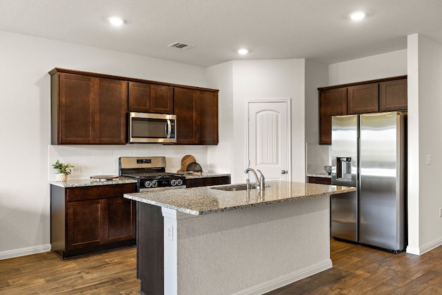 809 Cade Cv, Georgetown, TX 78626 - kitchen with appliances with stainless steel finishes, a sink, dark wood-type flooring, light stone counters, and dark brown cabinetry