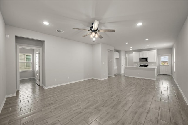521 Rearing Mare Pass, Georgetown, TX 78626 - unfurnished living room featuring light wood-style floors, a ceiling fan, baseboards, plenty of natural light, and recessed lighting