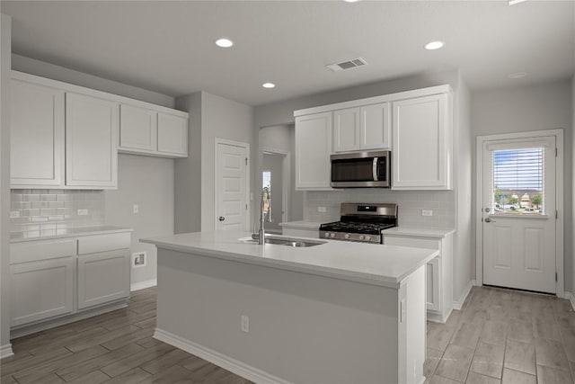 521 Rearing Mare Pass, Georgetown, TX 78626 - kitchen featuring appliances with stainless steel finishes, a sink, decorative backsplash, light wood-style flooring, and white cabinetry