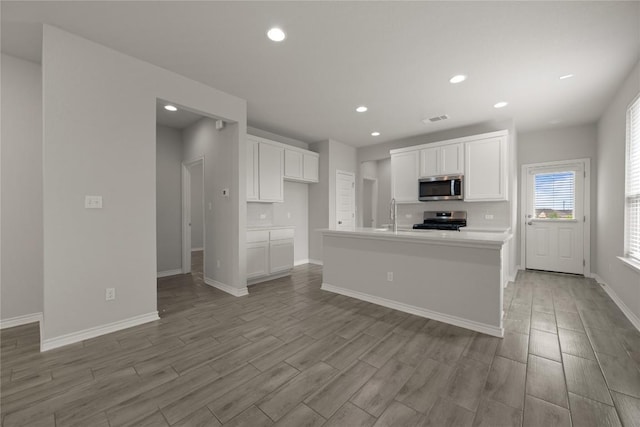 521 Rearing Mare Pass, Georgetown, TX 78626 - kitchen with stainless steel microwave, range, light wood-style flooring, recessed lighting, and white cabinetry