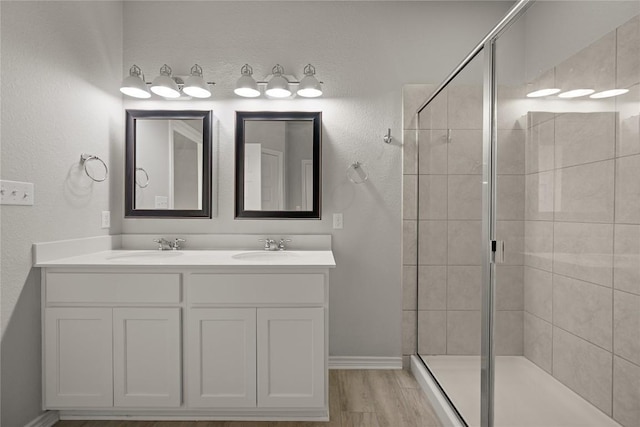 521 Rearing Mare Pass, Georgetown, TX 78626 - bathroom featuring a stall shower, double vanity, baseboards, and wood finished floors