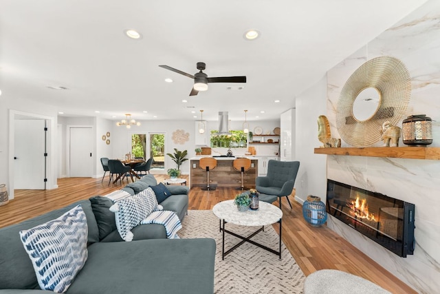 5102 Ravensdale Ln, Austin, TX 78723 - living room with a high end fireplace, a ceiling fan, recessed lighting, light wood-style flooring, and a chandelier