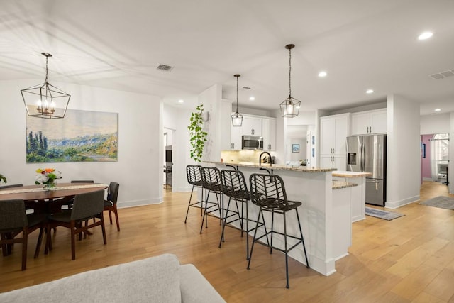 3400 Lynnbrook Dr, Austin, TX 78748 - kitchen with stainless steel appliances, baseboards, recessed lighting, a kitchen bar, and light wood-style flooring