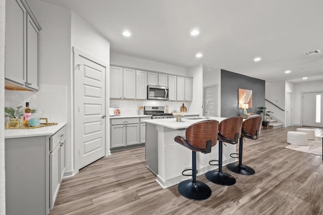 7809 Linnie Ln, Austin, TX 78724 - kitchen with stainless steel appliances, gray cabinetry, light wood finished floors, decorative backsplash, and recessed lighting