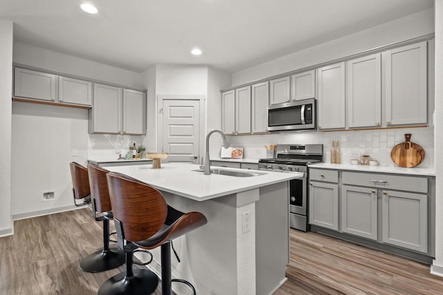 7809 Linnie Ln, Austin, TX 78724 - kitchen featuring stainless steel appliances, gray cabinetry, backsplash, light wood-style flooring, and recessed lighting