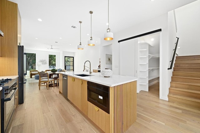 3507 Neal St Unit 1, Austin, TX 78702 - kitchen with black appliances, a sink, a barn door, modern cabinets, and light wood-style floors