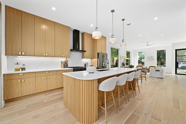 3507 Neal St Unit 1, Austin, TX 78702 - kitchen with wall chimney range hood, light wood-style flooring, light countertops, a kitchen island with sink, and recessed lighting
