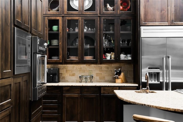 111 Piazza Vetta Dr, Austin, TX 78734 - kitchen with built in appliances, dark brown cabinetry, glass insert cabinets, and tasteful backsplash